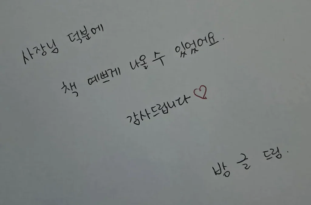 책 면지에 검은 펜으로 쓴 손글씨 — '사장님 덕분에 책 예쁘게 나올 수 있었어요. 감사드립니다' 옆에 빨간 하트, 아래에 '방글 드림'